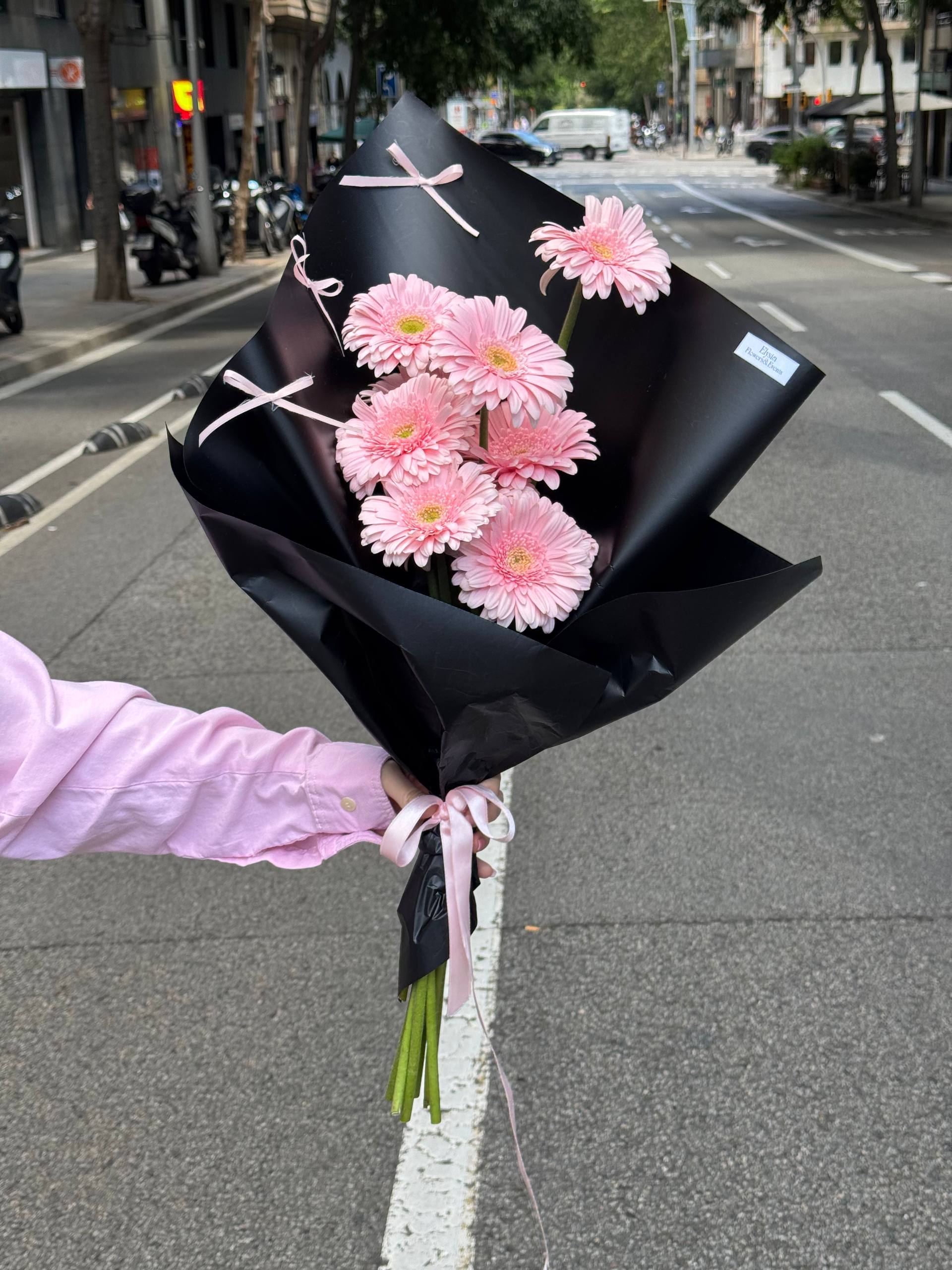 Bouquet of pink flowers wrapped in black paper on a street corner Bouquet of pink flowers wrapped in black paper on a street corner