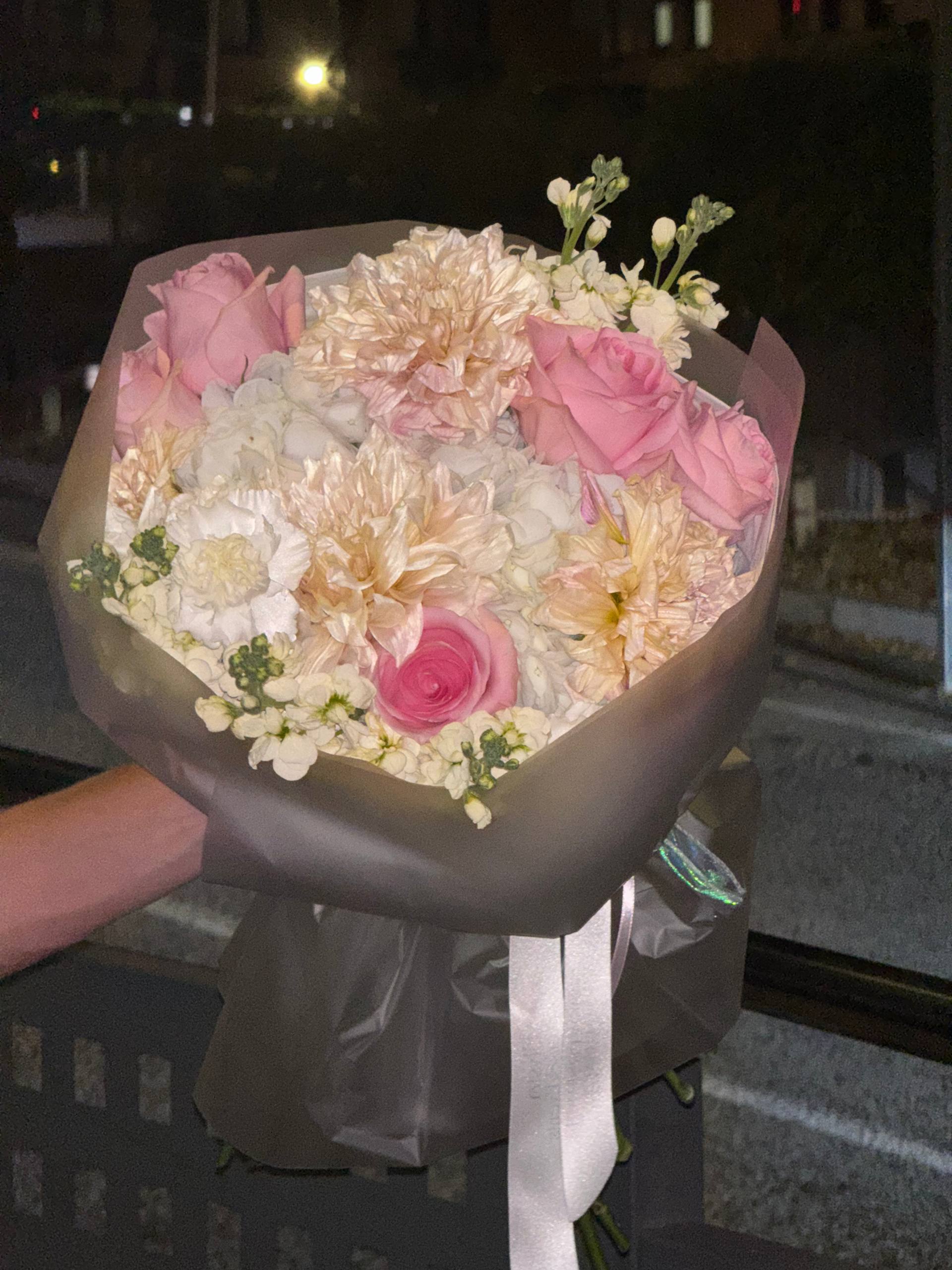 Bouquet of pink and white flowers held by a person at night. Ramo de flores rosadas y blancas sostenidas por una persona por la noche.