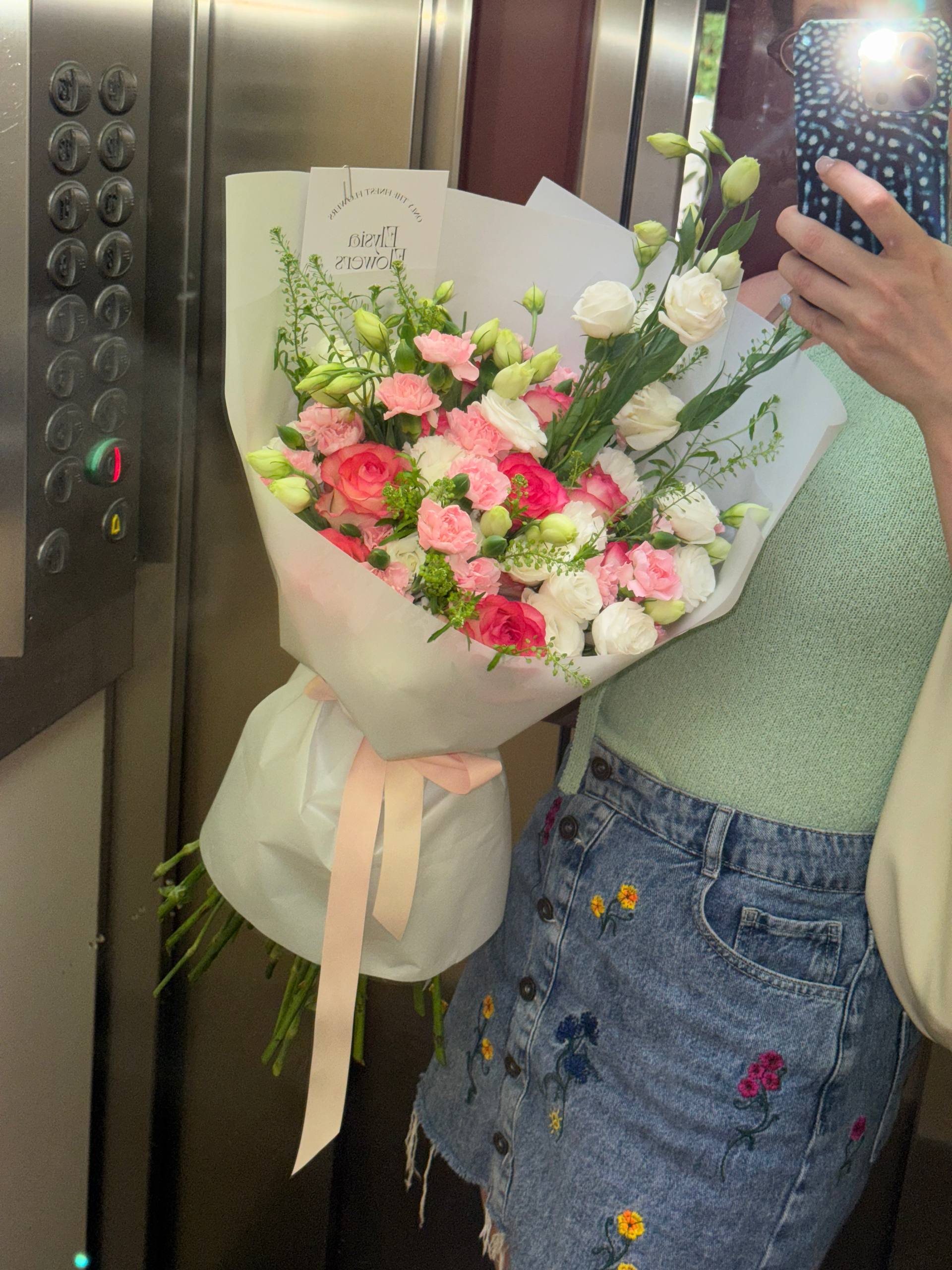 Person holding a bouquet of flowers in an elevator Persona sosteniendo un ramo de flores en un ascensor.