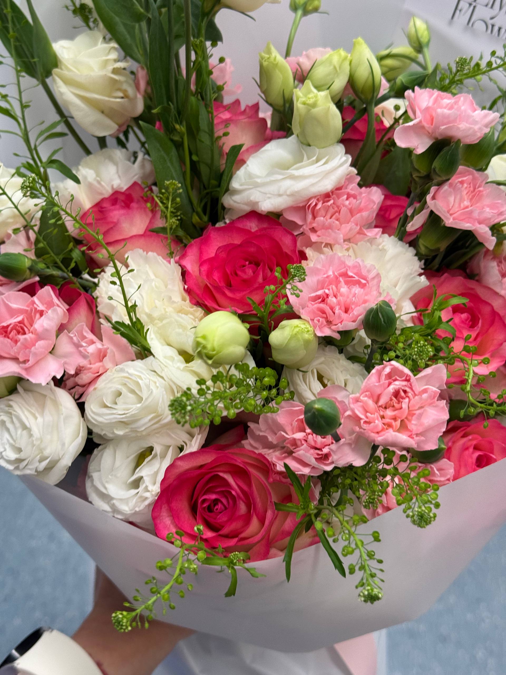 Bouquet of pink, white, and green flowers in a white paper wrap. Ramo de flores rosas, blancas y verdes en una envoltura de papel blanco.