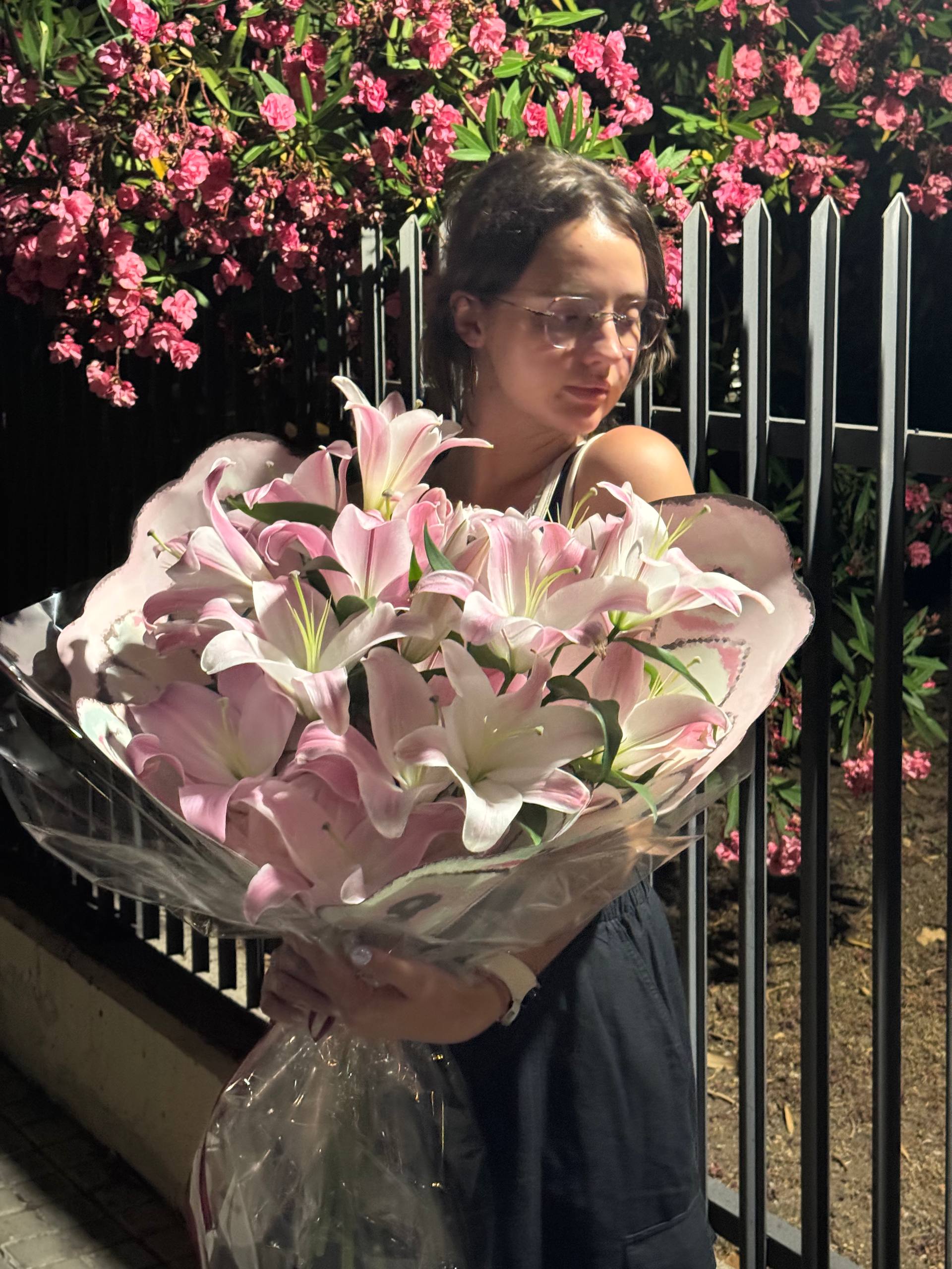 Person holding a large bouquet of pink flowers with a blurred background Persona sosteniendo un gran ramo de flores rosadas con un fondo borroso