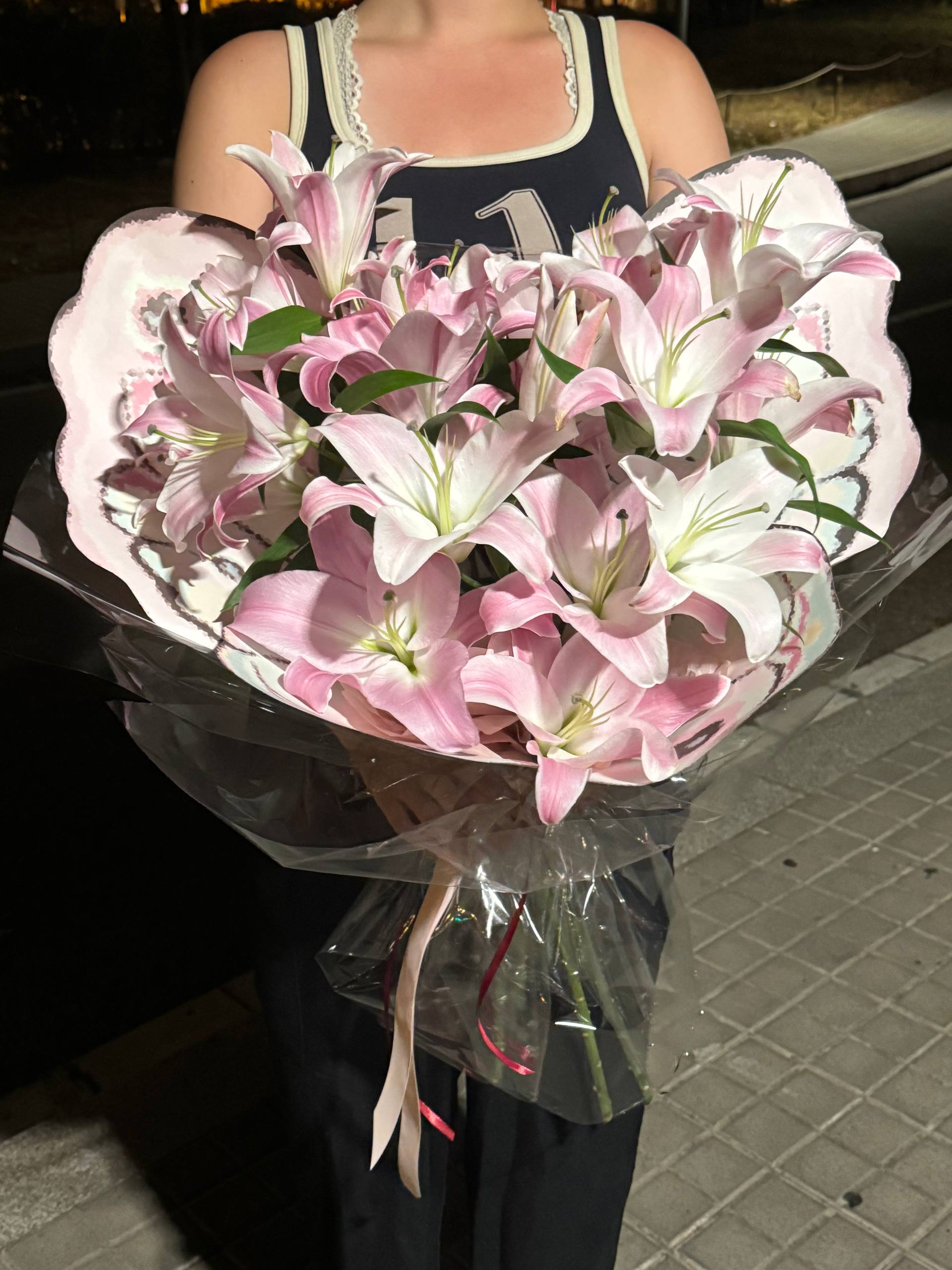 Bouquet of pink and white flowers held by a person on a dark background Ramo de flores rosadas y blancas sostenidas por una persona sobre un fondo oscuro