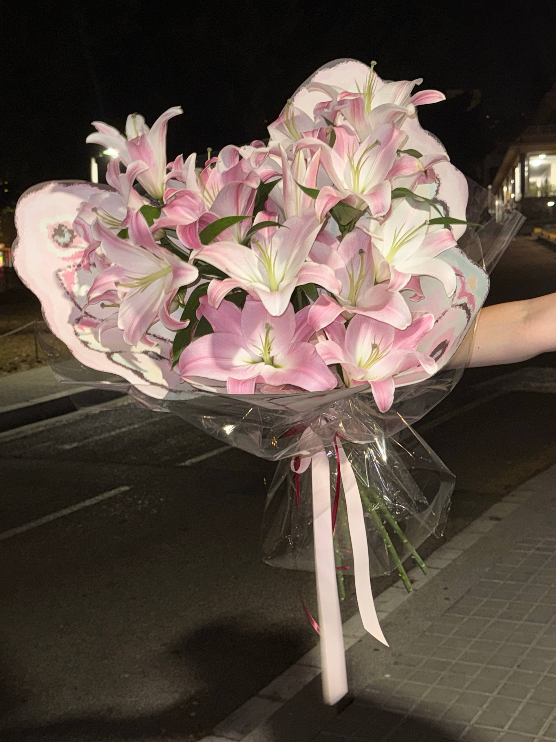 Bouquet of pink and white flowers held by a person at night. Ramo de flores rosadas y blancas sostenidas por una persona por la noche.