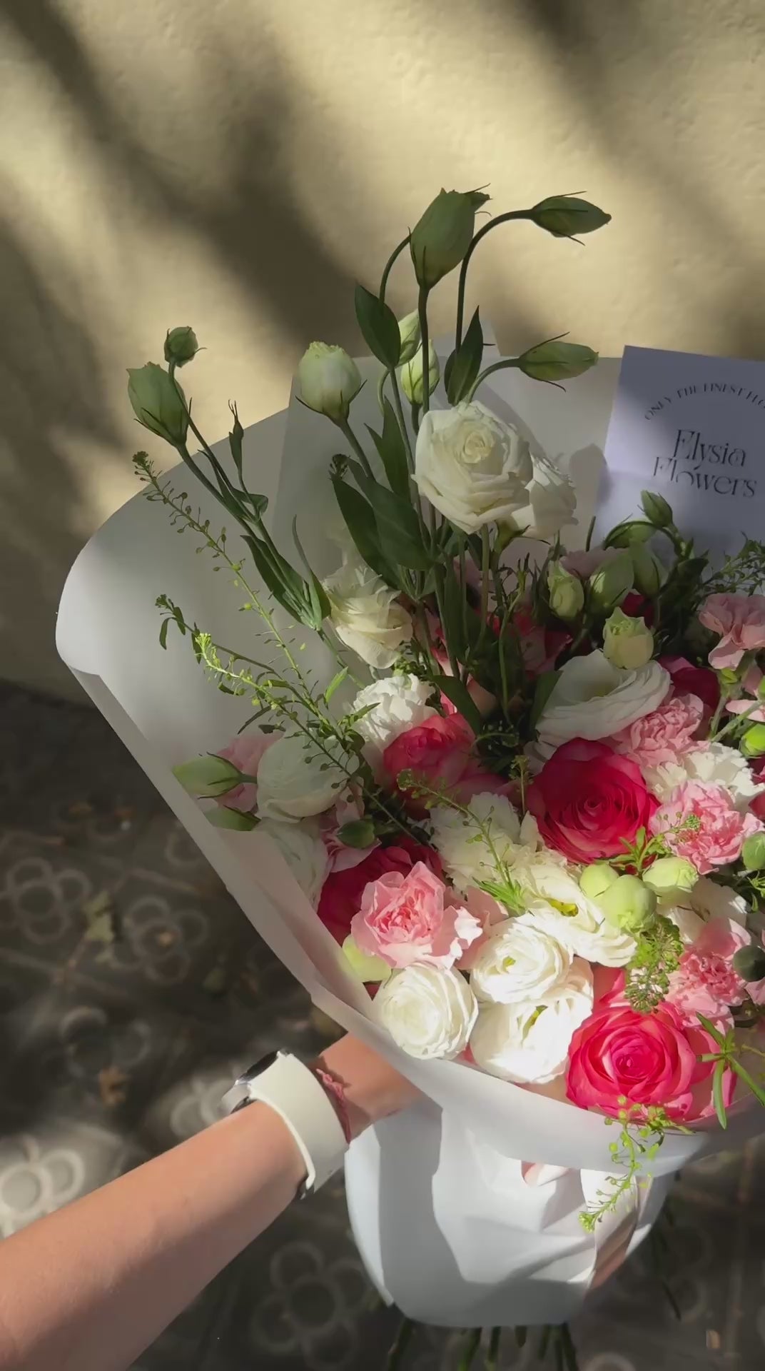 Bouquet of pink, white, and green flowers in a white paper wrap. Ramo de flores rosas, blancas y verdes en una envoltura de papel blanco.
