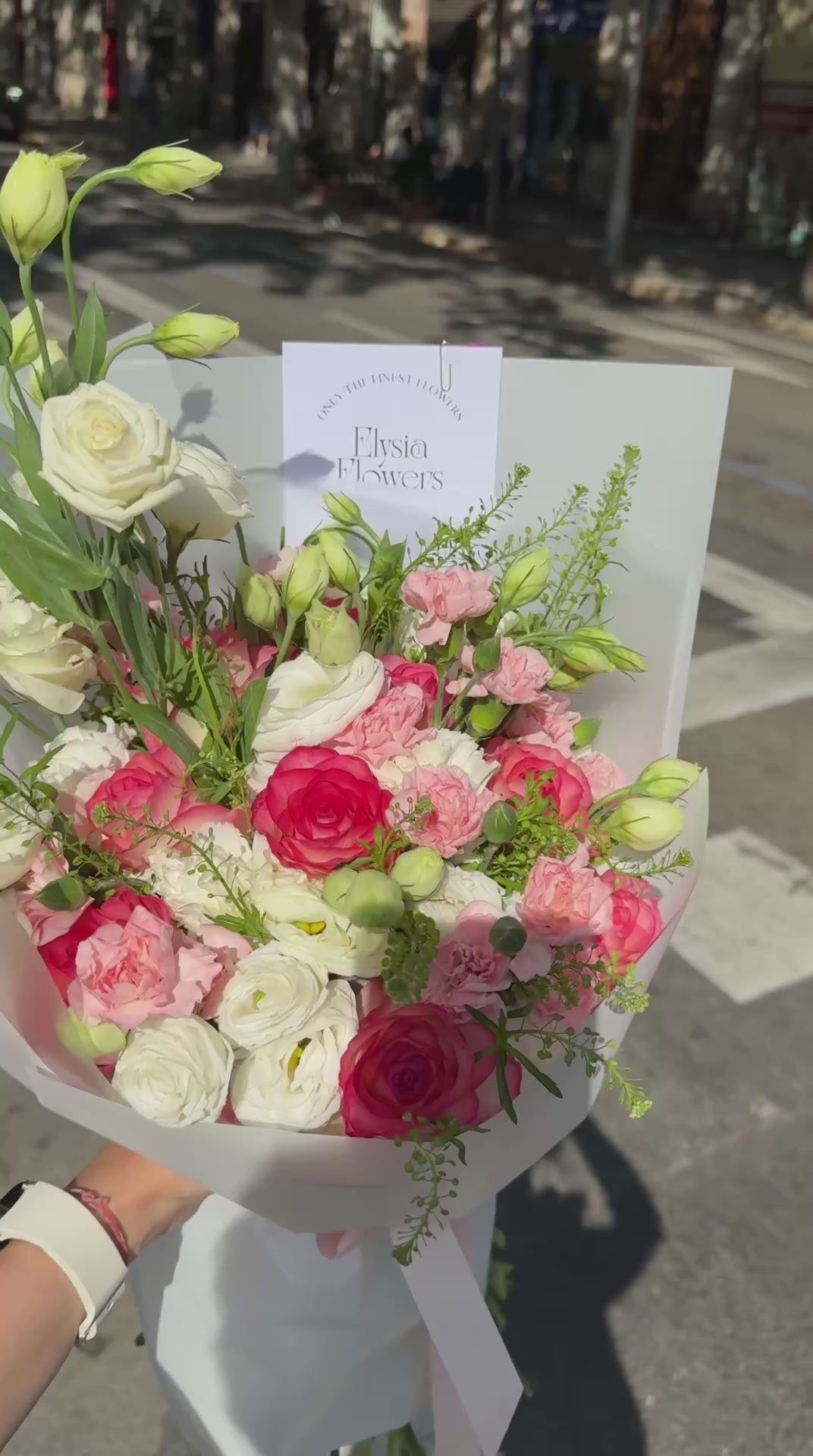 Person holding a bouquet of flowers in the street Persona sosteniendo un ramo de flores en la calle.
